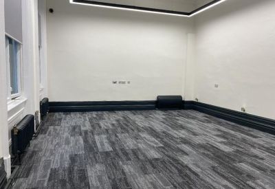 Spacious interior room with dark grey patterned carpet and white walls.