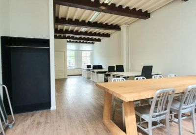 Open-plan workspace with exposed wood beam ceilings and large dining-style meeting table.