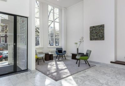 Modern lobby area with marble floors, colorful designer chairs, and large windows.
