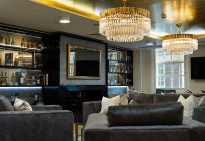 Sophisticated lounge area with gold ceilings, crystal chandeliers, and plush grey sofas.