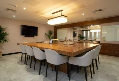 Professional meeting room with a large wooden table and grey upholstered chairs.
