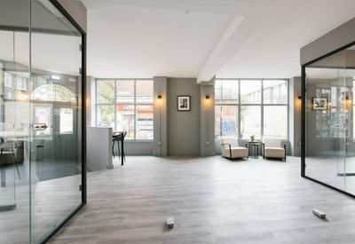 Central hallway area showing glass office entrances and a small seating nook with armchairs.