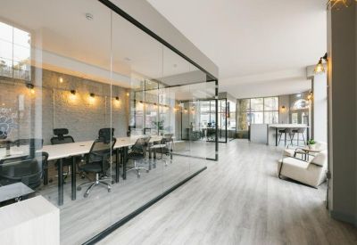 Open-plan office space featuring glass-walled suites and light wood flooring.
