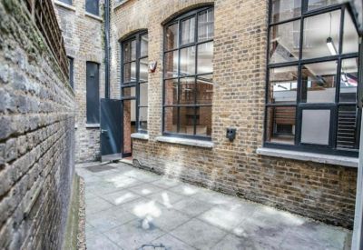 Small private outdoor courtyard paved with stone tiles next to brick building.