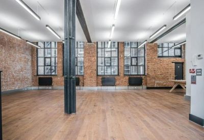 Large industrial-style workspace featuring high ceilings and expansive windows.