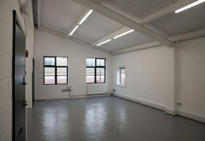 Bright, open-plan office space with white walls, grey floors, and large windows.