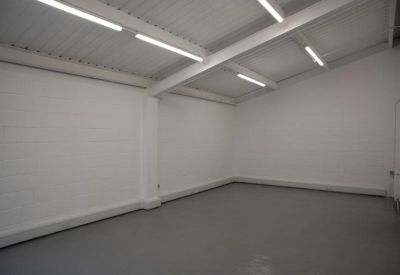 Spacious empty studio with vaulted ceilings and industrial overhead lighting.