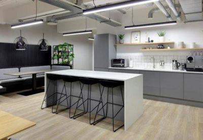 Sleek office kitchen and breakout area with a large island, grey cabinetry, and bar stool seating.