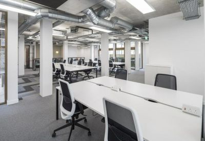 Bright open-plan workspace with white desks and industrial ceiling details.