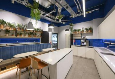 Communal kitchen and breakout area with blue walls, plants, and breakfast bar seating.