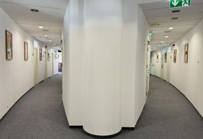 Symmetrical white corridor leading to various private office suites.