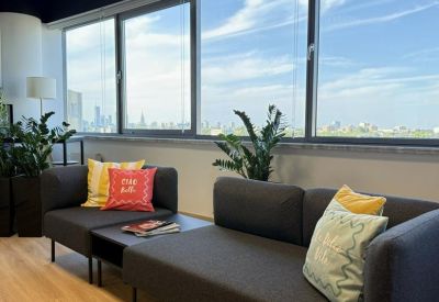 Relaxed lounge area with grey sofas, colorful pillows, and expansive windows.