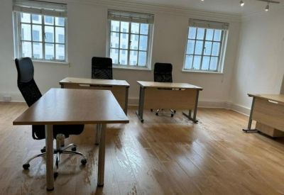 Spacious office suite with natural light from three large windows and wooden flooring.