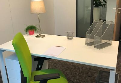 Bright private office featuring a green ergonomic chair and a white desk with a lamp.