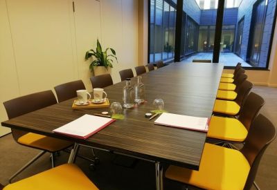 Boardroom with a dark wood table and bright yellow upholstered chairs.