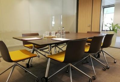 Meeting room with yellow-seated chairs around a large wooden conference table.
