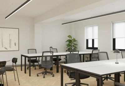 Open-plan workspace with multiple desks and chairs, featuring a large plant.