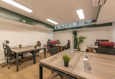 Modern open-plan office with wooden desks, ergonomic chairs, and a skylight providing natural light.