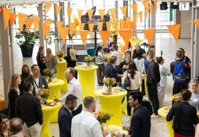 Spacious communal event area with orange bunting and yellow high-top tables.