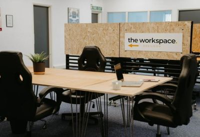 Collaborative workspace featuring long wooden tables and branded dividers.