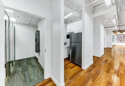 Modern communal kitchen with stainless steel appliances and polished wood flooring.