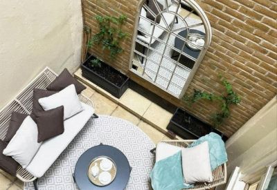 High-angle view of an outdoor courtyard with a round rug, seating, and a large arched mirror.