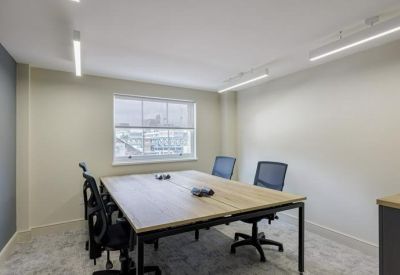 Light-filled private office with a wooden desk and blue ergonomic chairs.