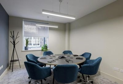 Bright meeting room with a round table and teal velvet chairs.