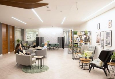 Spacious communal lounge with grey armchairs and a modern bookshelf partition.