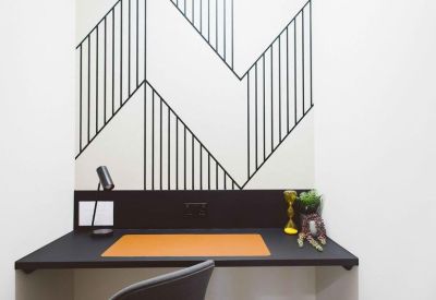 Private work booth featuring a black desk and a striking geometric wall mural.