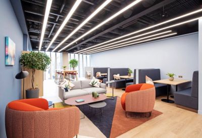 Colorful lounge area with plush armchairs and striped ceiling lights.