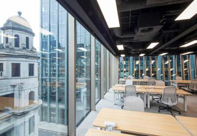 Bright coworking space with rows of desks and views of a historic building dome.