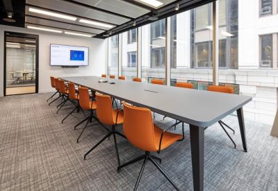 Spacious boardroom featuring a long grey table and orange executive chairs.