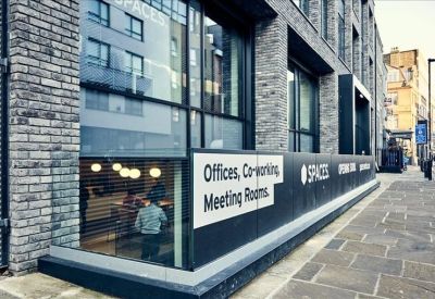 Signage for Spaces office units on a glass and brick building facade.