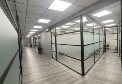 A long office corridor at 71 Grammou, Maroussi, Greece featuring glass partitions and recessed lighting.