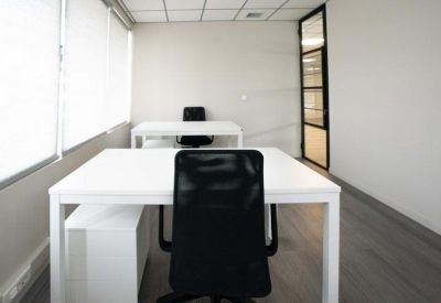 Private office space featuring two white desks and a glass door entrance.
