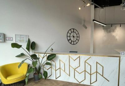 Modern marble reception desk with gold geometric patterns and a yellow armchair.