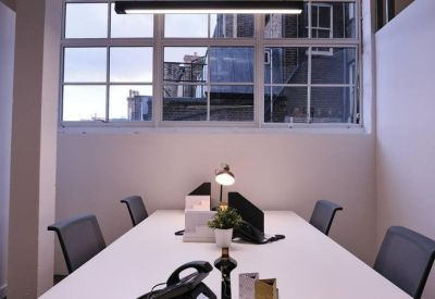 Four-person office suite with white desks, ergonomic chairs, and a desk lamp.