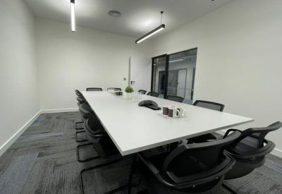 Long professional meeting room with a white table, black chairs, and hanging linear lights.