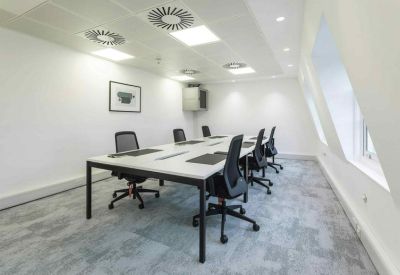 Sleek meeting room featuring a long white conference table and black mesh chairs.