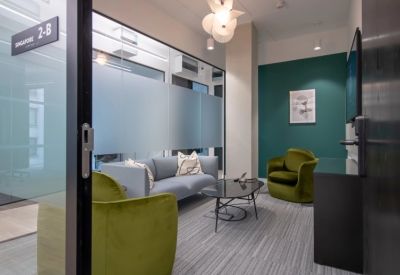 Cozy breakout room with a grey sofa, velvet green armchairs, and a teal feature wall.