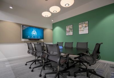 Modern meeting room featuring a green accent wall, abstract art, and pendant lighting.