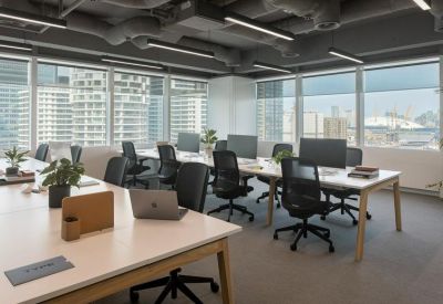 Open-plan workspace with white desks, ergonomic black chairs, and large windows with city views.