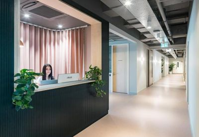 Stylish reception desk with a dark fluted front, wooden accents, and a pink curtain backdrop.