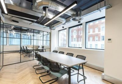 Bright boardroom with a long white table and black chairs set against a glass partition wall.