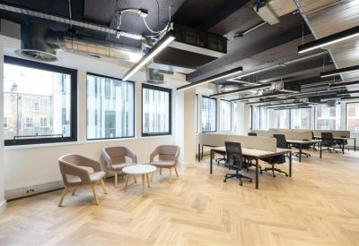 Relaxed lounge area with grey armchairs, a coffee table, and views through large windows.