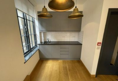 Compact kitchen area with dark countertops and warm wood-effect flooring.