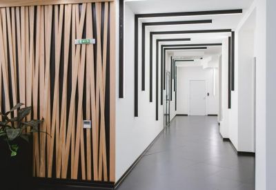 Modern white corridor with rhythmic black ceiling slats and a decorative wood-paneled feature wall.