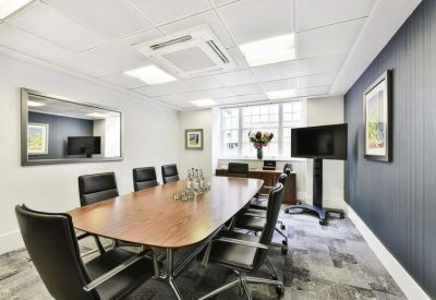 Meeting room with a wooden table, black leather chairs, and a navy blue feature wall.