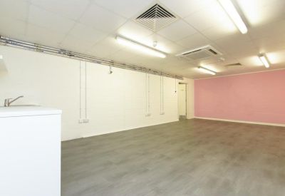 Spacious communal area with a pink feature wall and recessed ceiling lighting.